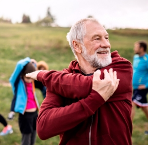 Large group of fit and active people doing exercise in nature, stretching